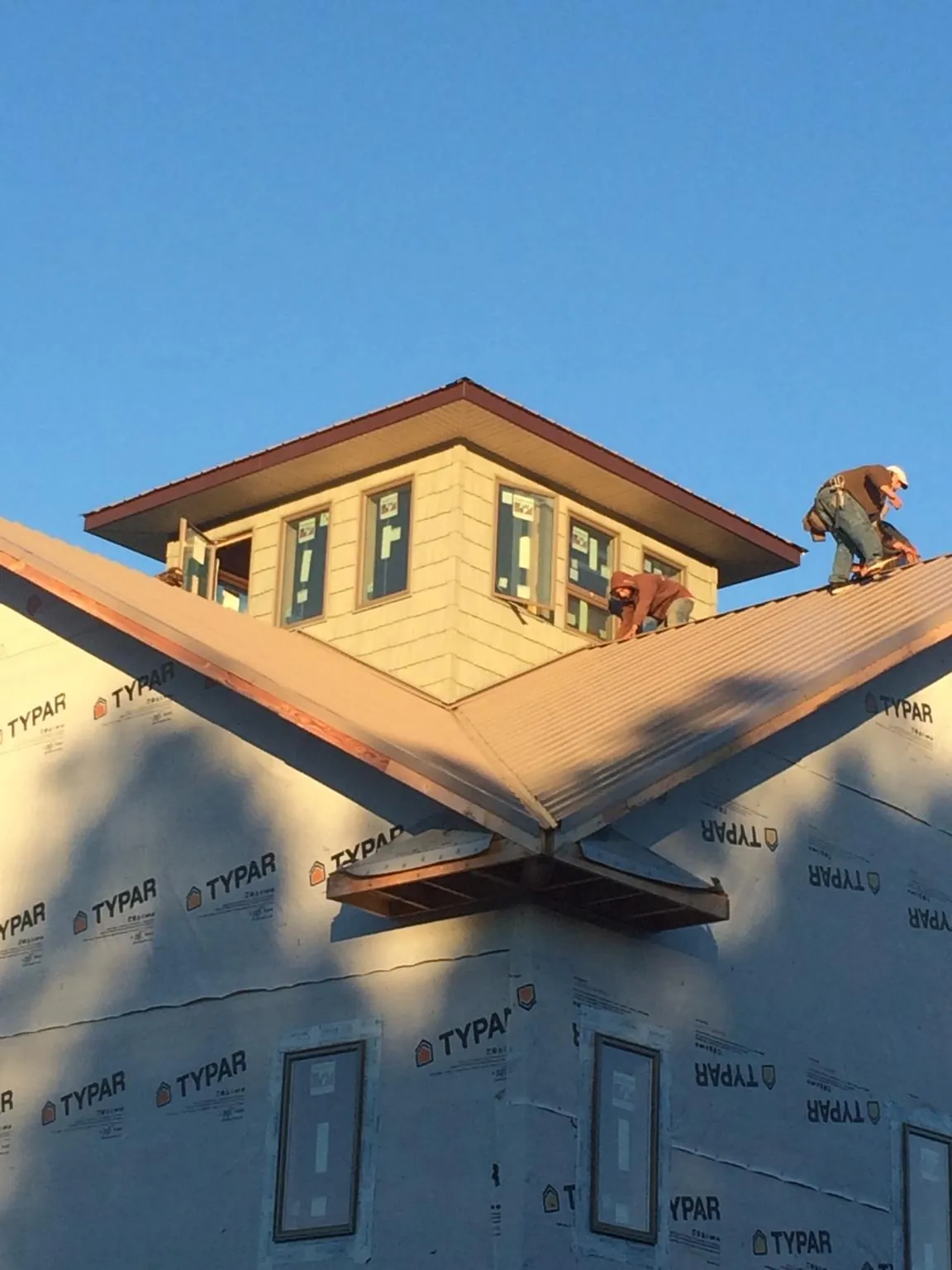 Roofers working around a rooftop cupola on a new metal roof at sunset — Roof Waterproofing in Rockford by Roofing Brothers